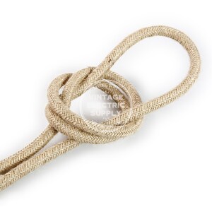 Puede incluir: Primer plano de un cord&oacute;n de algod&oacute;n trenzado de color natural. El cord&oacute;n est&aacute; retorcido en un nudo, mostrando la textura de la tela.