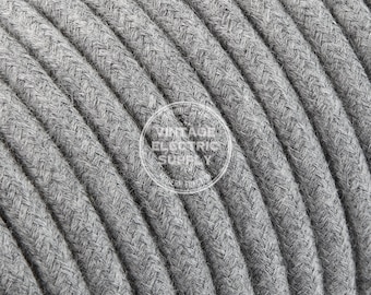May include: Close-up of a spool of gray braided fabric electrical cord. The cord has a herringbone pattern and is wound tightly.