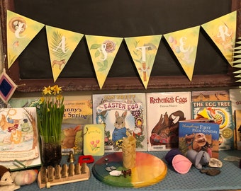 May include: A colorful Easter-themed classroom display with books, a banner, and toys. The banner reads "Easter" in yellow and green letters. The books include titles like "The Easter Egg" and "Rechenka's Eggs".