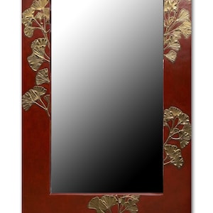May include: A rectangular wall mirror with a deep red frame featuring embossed gold-colored ginkgo leaf motifs along the edges. The mirror measures 24 inches by 35 inches, as indicated by the text at the bottom, and has a reflective glass center.
