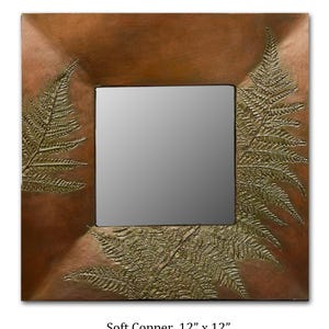 May include: A square mirror with a copper frame and a fern design. The frame is 12 inches by 12 inches and has a soft copper finish.