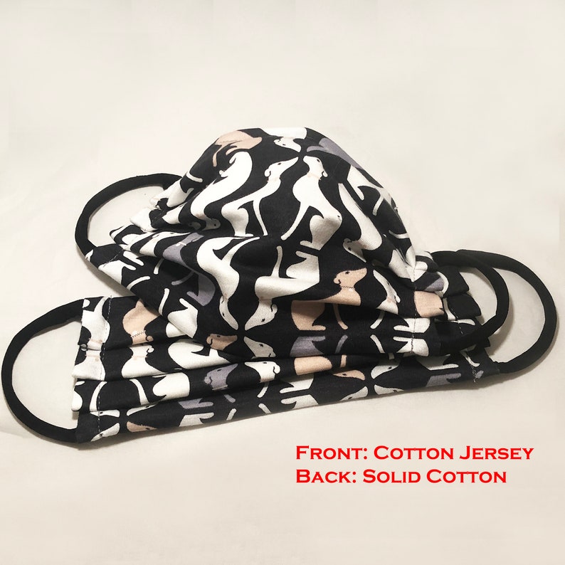 May include: Two face masks with black ear loops. The masks are made of cotton jersey and solid cotton. The front of the masks have a repeating pattern of white, gray, and tan dog silhouettes on a black background.