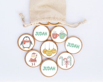 May include: A set of seven wooden Christmas-themed ornaments with a white background and colorful illustrations. The ornaments feature a penguin, Santa Claus, candy canes, a hot chocolate mug, and Christmas ornaments. The ornaments are in a small white drawstring bag.