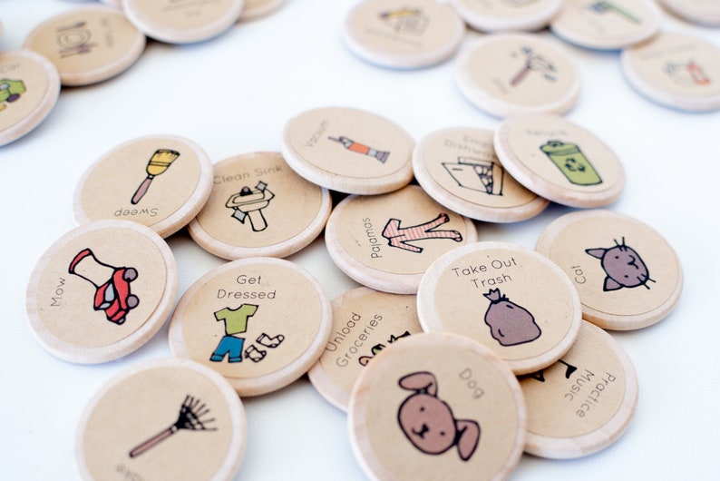Pu&ograve; includere: Un set di 15 gettoni rotondi in legno con varie illustrazioni e testo. I gettoni presentano immagini di un gatto, un cane, un sacchetto della spazzatura, un tosaerba, una scopa, un lavandino, vestiti, pigiama, generi alimentari e un rastrello. Il testo sui gettoni include "Falciare", "Spazzare", "Vestirsi", "Pulire il lavandino", "Scaricare la spesa", "Cane", "Pigiama", "Portare fuori la spazzatura", "Gatto" e "Esercitarsi con la musica".