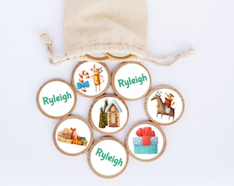 May include: A collection of wooden Christmas-themed tokens with illustrations of a reindeer, gifts, a house, and a dog riding a horse. Each token has the name "Ryleigh" printed in green. The tokens are displayed with a beige drawstring bag.