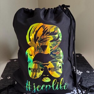 May include: Black drawstring bag with a holographic gold and green graphic of a woman wearing sunglasses with the text "#jeeplife" printed below.