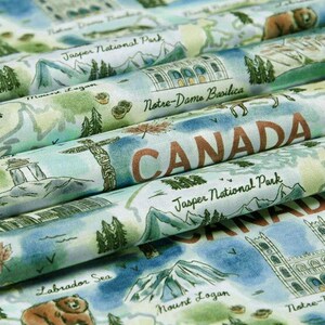 May include: Fabric with a map of Canada featuring landmarks like Notre-Dame Basilica and Jasper National Park. The design includes illustrations of a bear, mountains, and the text "CANADA" in a rustic font. The color palette is soft, with blues, greens, and browns.