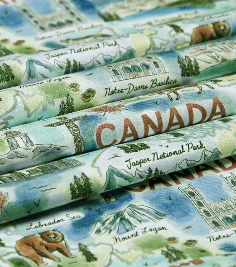 May include: Fabric with a map of Canada featuring landmarks like Notre-Dame Basilica and Jasper National Park. The design includes illustrations of a bear, mountains, and the text "CANADA" in a rustic font. The color palette is soft, with blues, greens, and browns.