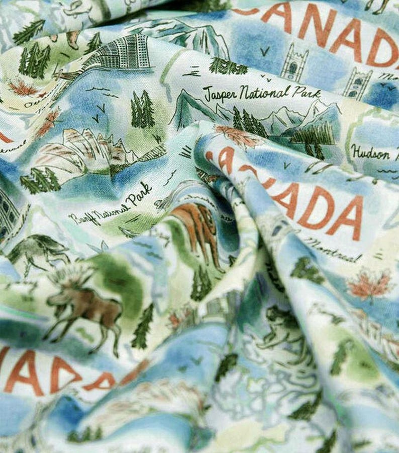 May include: A fabric with a map of Canada design. The fabric features illustrations of mountains, trees, and wildlife, with text including "Canada", "Jasper National Park", and "Banff National Park". The color palette includes shades of blue, green, and brown.