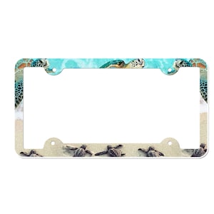 May include: White plastic license plate frame with a colorful image of sea turtles swimming in blue water. The frame has two holes on each side for attaching to a license plate.