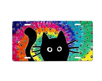 Puede incluir: Una silueta de gato negro con ojos grandes sobre un fondo de tie-dye colorido con huellas de patas. El fondo es un arcoíris de colores con un patrón de espiral.