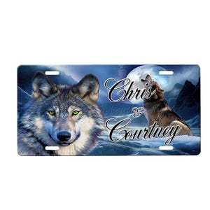 May include: A blue and white personalized license plate featuring a howling wolf silhouette against a full moon. The text "Chris & Courtney" is printed in black.