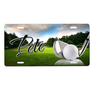 May include: A personalized golf-themed license plate with a green golf course background, a golf club with a golf ball, and the name "Pete" in black cursive lettering.