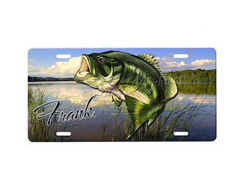 Può includere: Una targa personalizzata con un pesce persico verde e marrone che salta fuori dall'acqua. La targa ha il nome "Frank" stampato su di essa.