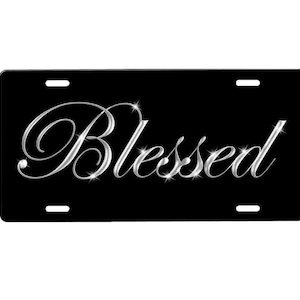 May include: Black license plate with the word "Blessed" in silver script with sparkling accents.