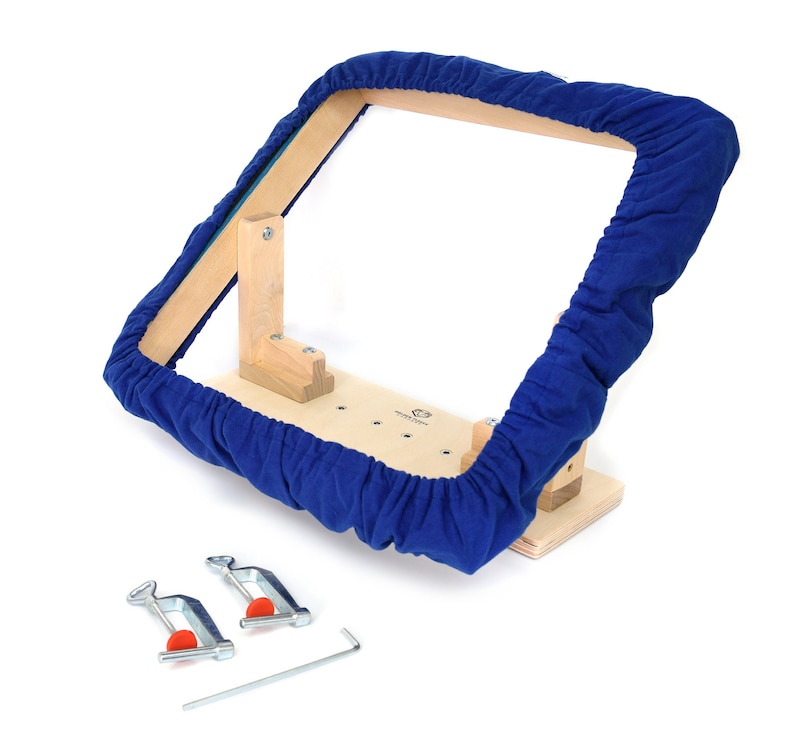 May include: A wooden embroidery hoop frame with a blue fabric cover. The frame is attached to a wooden base with two clamps and a wrench.