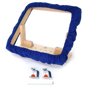 May include: A wooden embroidery hoop with a blue fabric cover. The hoop is attached to a wooden base with two clamps and a wrench.