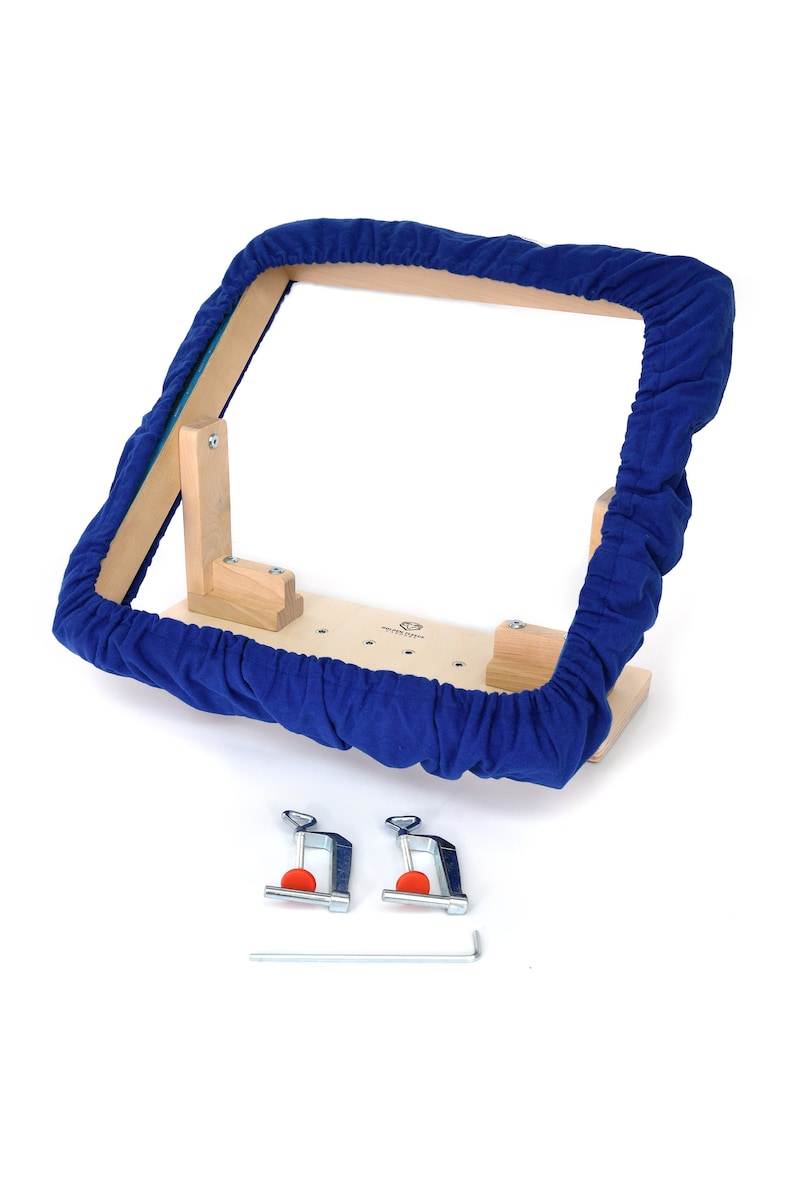 May include: A wooden embroidery hoop with a blue fabric cover. The hoop is attached to a wooden base with two clamps and a wrench.
