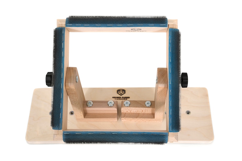 May include: Wooden frame with blue felt and black knobs, used for stretching and finishing needle felted projects. The frame is labeled "Golden Fleece Carded".