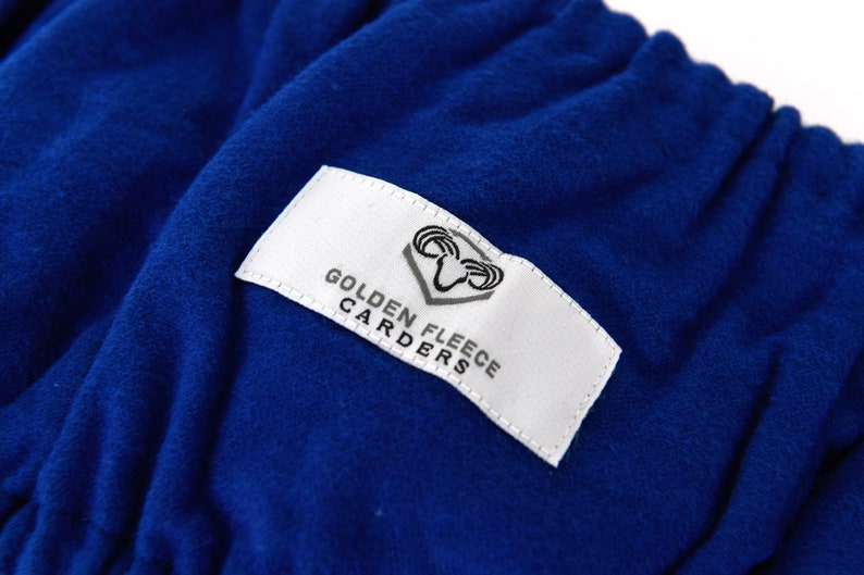 May include: A white label with black text and a ram logo reads "Golden Fleece Carders". The label is sewn onto a royal blue fabric.
