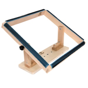 May include: Wooden embroidery hoop stand with a blue padded hoop. The stand has a base with a knob for adjusting the angle of the hoop.