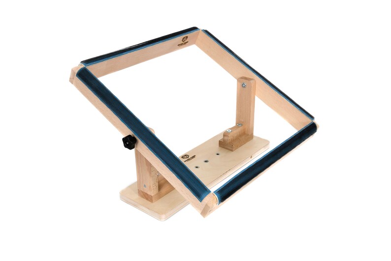 May include: Wooden embroidery hoop stand with a blue padded hoop. The stand has a base with a knob for adjusting the angle of the hoop.
