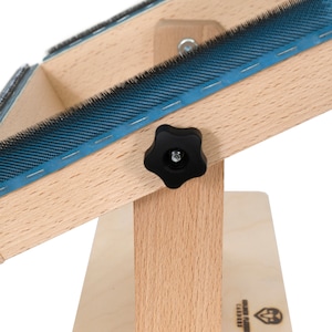 May include: A wooden brush board with a blue brush and a black knob to adjust the angle. The board is made of light wood and has a label on the bottom that says "Mountain Flame Carpathi"