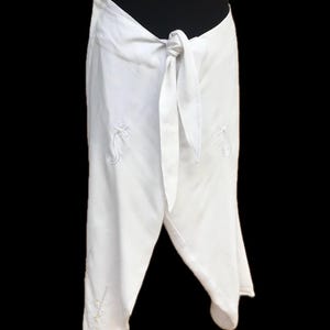 May include: White wrap skirt with a tie at the waist and embroidered floral designs.