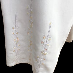 May include: White skirt with embroidered floral design featuring silver and gold sequins.
