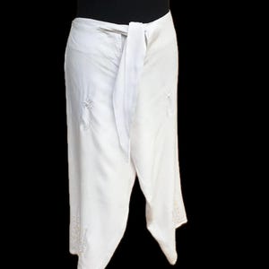 May include: White wrap skirt with a tie at the waist and embroidered details.