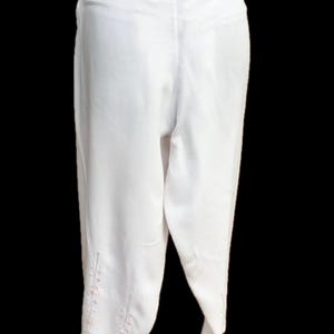 May include: White pants with a wide leg and embroidered details on the bottom.