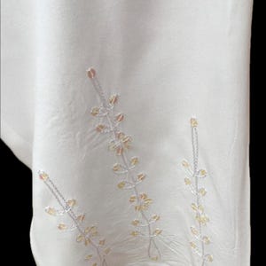 May include: White fabric with embroidered floral designs in shades of pink and yellow.