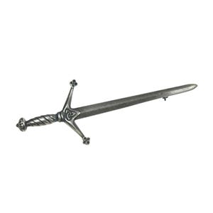 May include: A silver-toned metal brooch shaped like a sword. The hilt features a twisted handle design and a crossguard with a central triangular knotwork detail. The blade is straight and tapers to a point, with a pin mechanism visible.