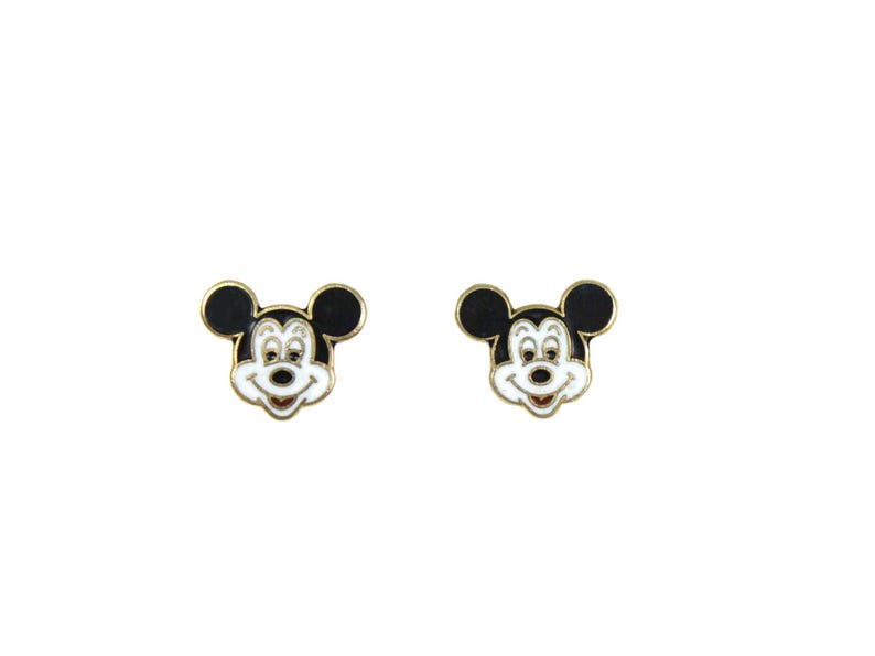 May include: A pair of Mickey Mouse stud earrings. Each earring features a gold-colored border with a black head and ears, a white face, and a red mouth. The earrings are set against a white background.