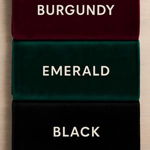 K&ouml;nnte beinhalten: Drei rechteckige Samtstoffmuster in Burgunderrot, Smaragdgr&uuml;n und Schwarz. Jedes Muster hat eine wei&szlig;e Textbeschriftung, die seine Farbe angibt: BURGUNDY, EMERALD und BLACK. Die Muster sind vertikal vor einem hellen Holzgrund gestapelt.