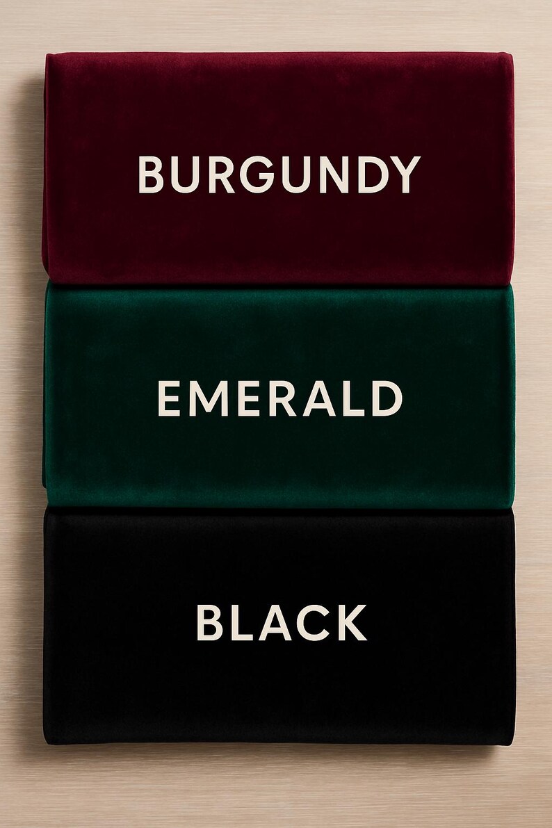 K&ouml;nnte beinhalten: Drei rechteckige Samtstoffmuster in Burgunderrot, Smaragdgr&uuml;n und Schwarz. Jedes Muster hat eine wei&szlig;e Textbeschriftung, die seine Farbe angibt: BURGUNDY, EMERALD und BLACK. Die Muster sind vertikal vor einem hellen Holzgrund gestapelt.