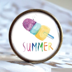 Könnte beinhalten: Ein runder, weißer Knopf mit einer Aquarell-Illustration eines bunten Eis am Stiel und dem Wort "SUMMER" in Regenbogenfarben.