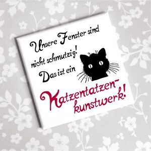 Könnte beinhalten: Weißer quadratischer Magnet mit einer Schwarzweißillustration einer Katze, die über den oberen Rand schaut. Der Text lautet "Unsere Fenster sind nicht schmutzig! Das ist ein Katzen-tatzen-kunstwerk!"