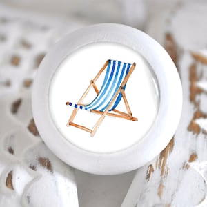 Könnte beinhalten: Weißer Keramik-Knopf mit einer Illustration eines blau-weiß gestreiften Strandstuhls.