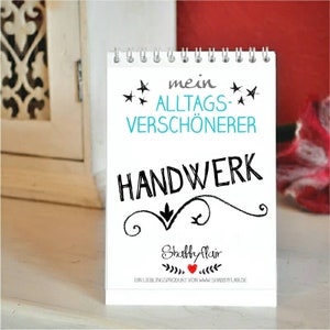 Könnte beinhalten: Ein weißer Notizblock mit einer schwarzen Spiralbindung. Der Notizblock hat eine schwarz-weiße Illustration eines stilisierten Wirbels mit einem nach unten zeigenden Pfeil. Der Text "mein ALLTAGS-VERSCHÖNERER HANDWERK" ist in Schwarz mit einem blauen Akzent auf "ALLTAGS-VERSCHÖNERER" geschrieben. Der Text "Shabby Flair" ist in Schwarz mit einem roten Herzen und einem grünen Blattdesign geschrieben. Der Text "EIN LIEBLINGSPRODUKT VON WWW.SHABBYFLAIR.DE" ist in Schwarz geschrieben.