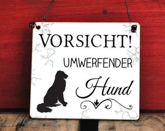 Könnte beinhalten: Ein weißes Schild mit schwarzem Text und einer Silhouette eines Hundes. Das Schild lautet "Vorsicht! Umwerfender Hund".