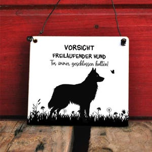Könnte beinhalten: Ein weißes quadratisches Schild mit schwarzem Text und einer Hundesilhouette. Der Text lautet "VORSICHT FREILAUFENDER HUND Tor immer geschlossen halten!". Ein Schmetterling und Gras sind ebenfalls abgebildet.