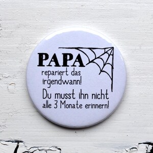 Könnte beinhalten: Weißer runder Knopf mit schwarzem Text, der "Papa repariert das irgendwann! Du musst ihn nicht alle 3 Monate erinnern!" lautet. Oben rechts auf dem Knopf befindet sich eine schwarz-weiße Spinnennetzgrafik.