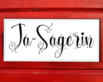 May include: White sign with black calligraphy that reads "Ja-Sagerin" with small hearts around the text.