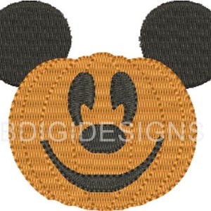 May include: Embroidered design featuring a smiling pumpkin face with black eyes, mouth, and ears. The pumpkin is orange with a textured appearance, and the ears are black. The text "BDIGIDESIGNS" is visible on the pumpkin.