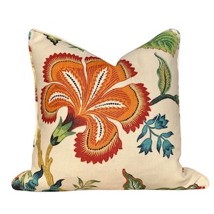 May include: A cream-colored pillow with a large orange, red, and blue floral design. The pillow features a large flower with intricate details and smaller floral accents.