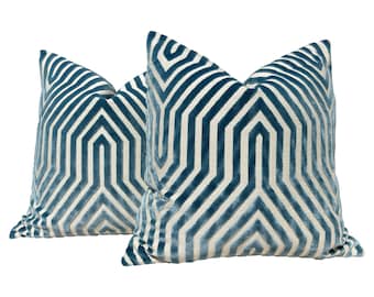 May include: Two teal blue velvet throw pillows with a white geometric pattern. The pillows are arranged side by side.
