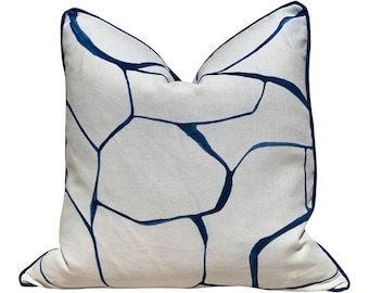 May include: A white throw pillow with a blue geometric pattern. The pillow has a blue trim around the edges.