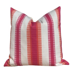 May include: A white pillow with pink and orange stripes. The pillow is made of a soft, textured fabric.