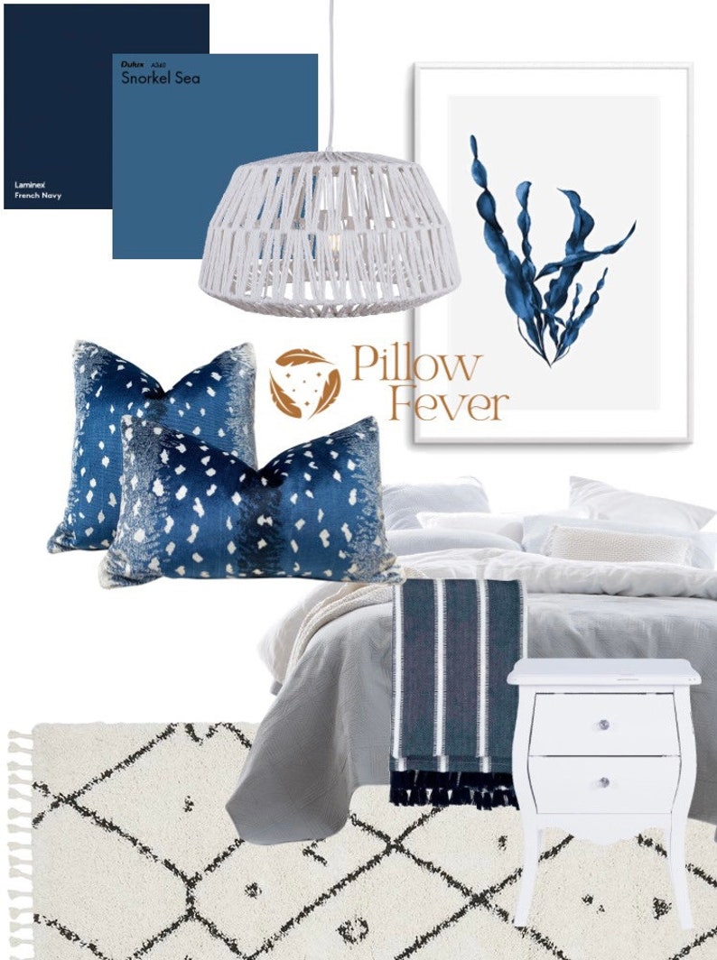 Pu&ograve; includere: Un letto bianco con biancheria da letto blu e bianca, un comodino bianco con due cassetti, una lampada a sospensione bianca intrecciata e un tappeto bianco con un motivo geometrico nero. Due cuscini decorativi blu e bianchi a motivi sono sul letto. Una stampa incorniciata con un disegno di alghe blu ad acquerello e il testo "Pillow Fever" &egrave; sul muro.